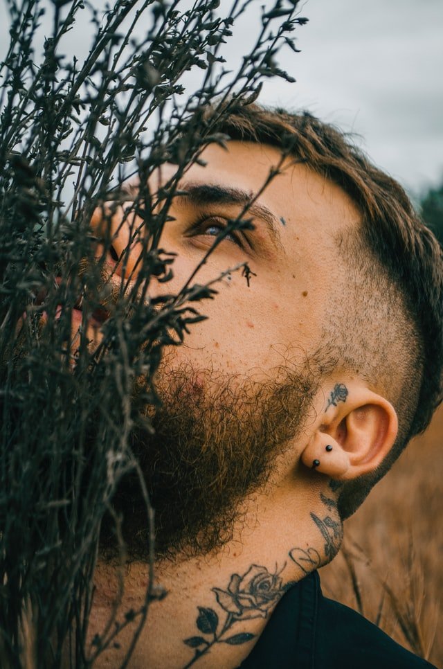 Homem com tatuagem de rosa na orelha 