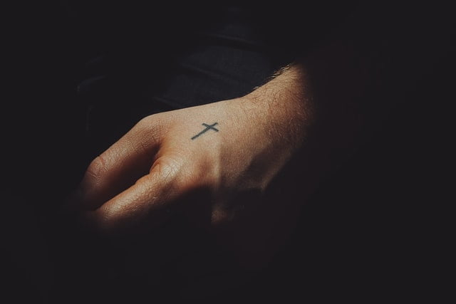 mão masculina com tatuagem de cruz
