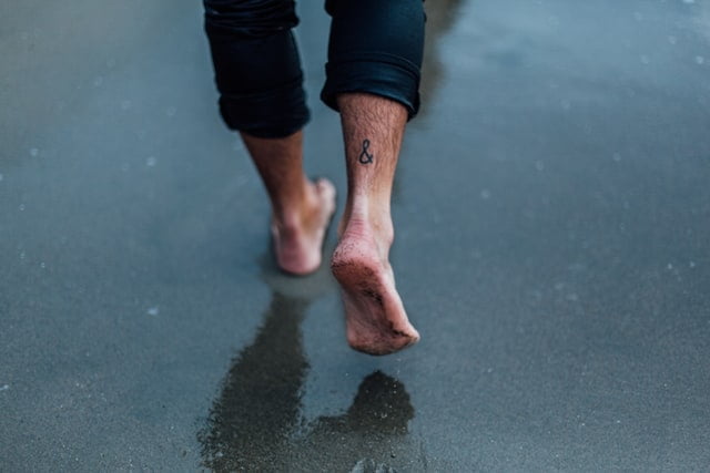 Homem com tatuagem de letra no tornozelo