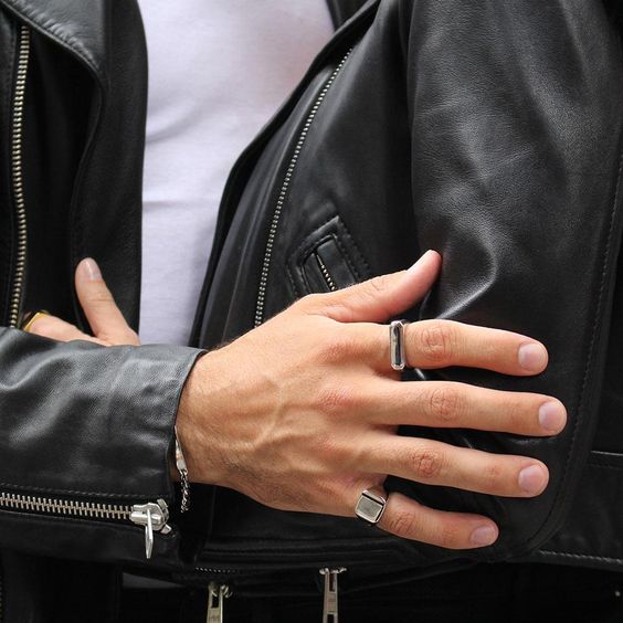 Mão branca com unhas masculinas feitas e usando anéis