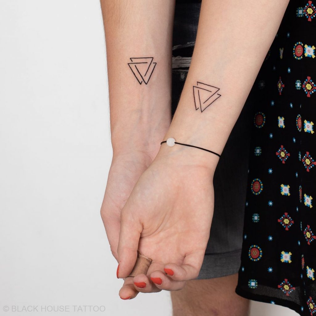Casal com tatuagem geométrica de triângulo duplo no pulso