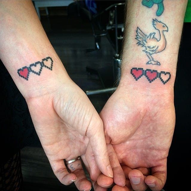 Foto de tatuagem pequena masculina no pulso de casal com corações de jogo de videogame