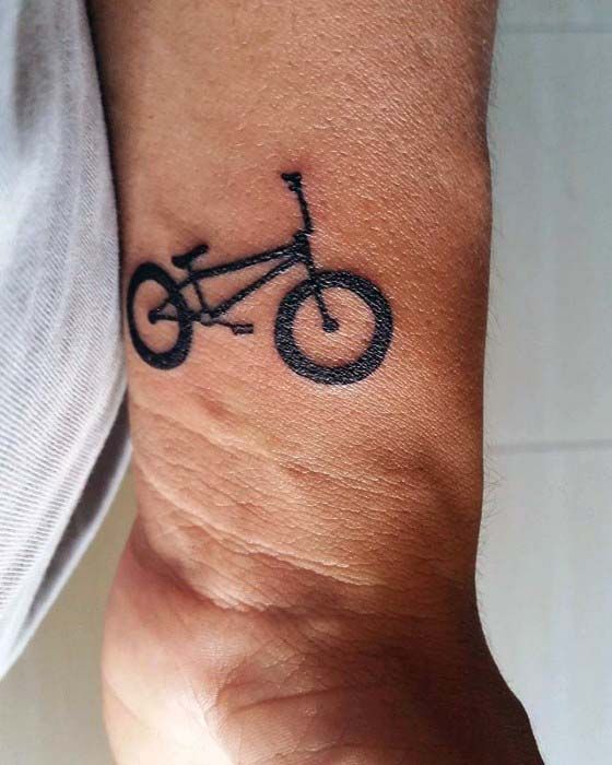 Pulso masculino com tatuagem de bicicleta em preto.