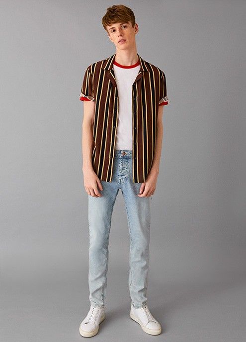 garoto de pé com camisa de manga curto e jeans claro, clássico dos anos 90