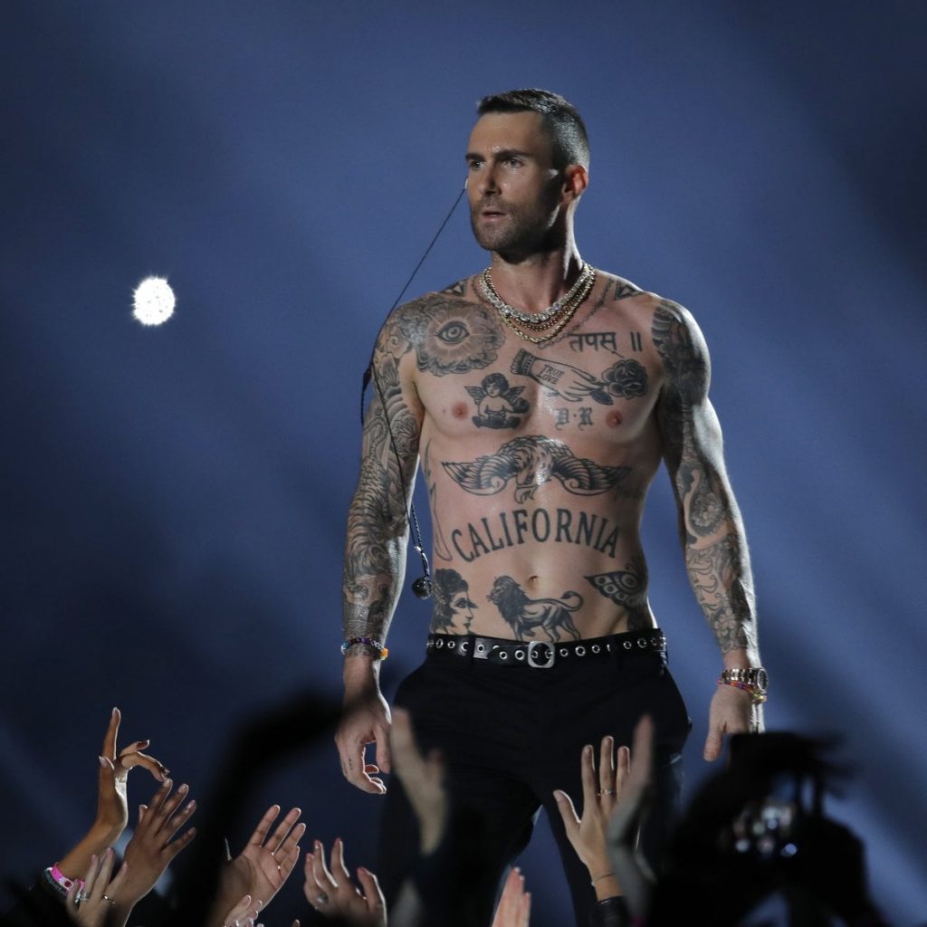 adam lavine em um show e suas tatuagens na cintura