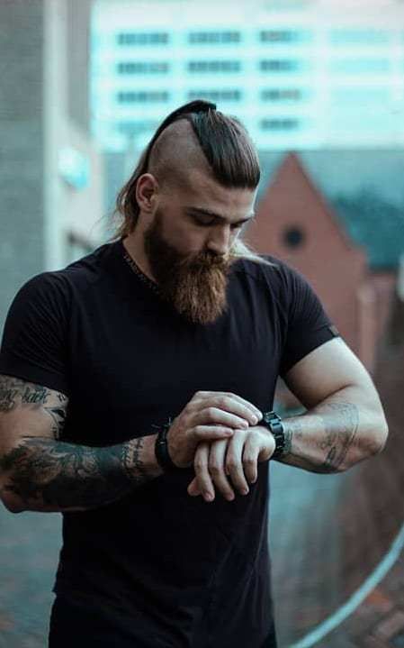 Homem com barba e  undercut com corte de cabelo viking cumprido