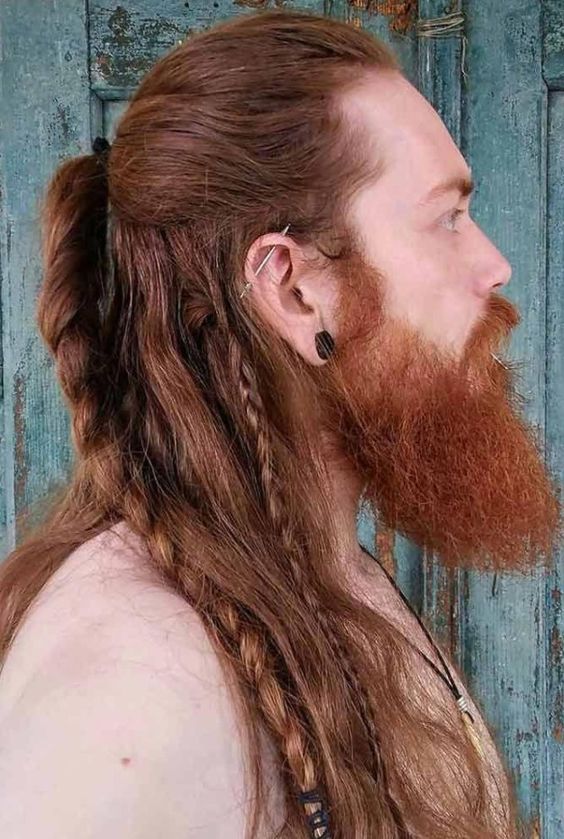 Perfil de homem ruivo com corte de cabelo viking longo com muitas tranças.