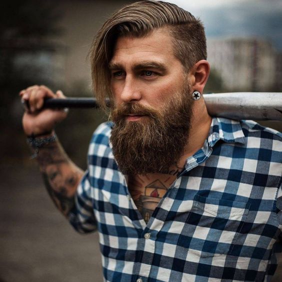 Imagem plano médio com homem de cabelo médio e barba rustica volumosa.