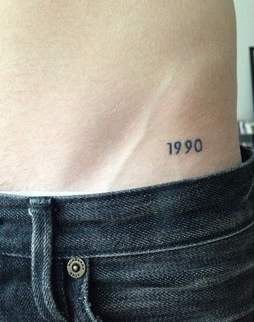 Close em tatuagem na virilha escrito '1990'