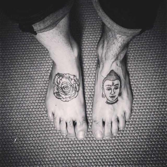 Close em pés com  duas tatuagens, uma rosa e o rosto de budha.