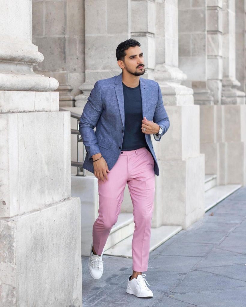 calça masculina rosa em homem vestindo blazer e caminhando ao sair de um edificio