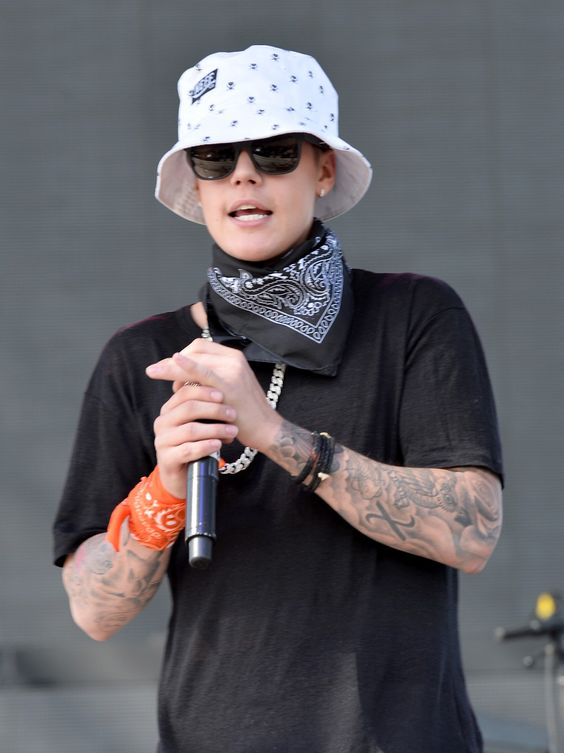 Close e m Justin Bieber usando um chapéu bucket masculino branco estampado com pequenos logotipos.