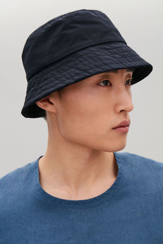 Close em asiático com  chapéu bucket masculino azul escuro quase preto.