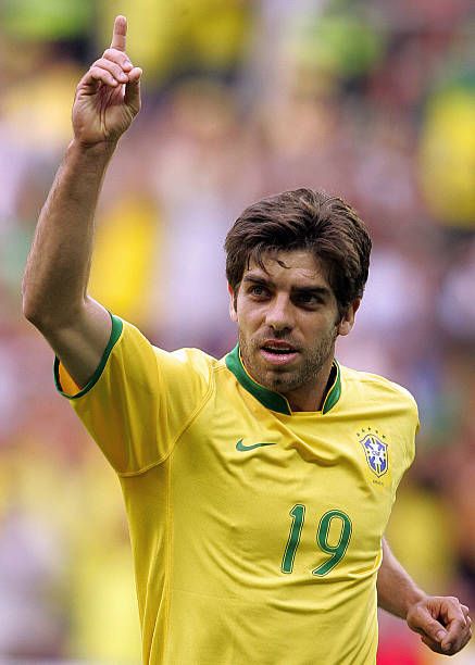 Juninho Pernambucano com o  uniforme da seleção brasileira com o dedo erguido para cima