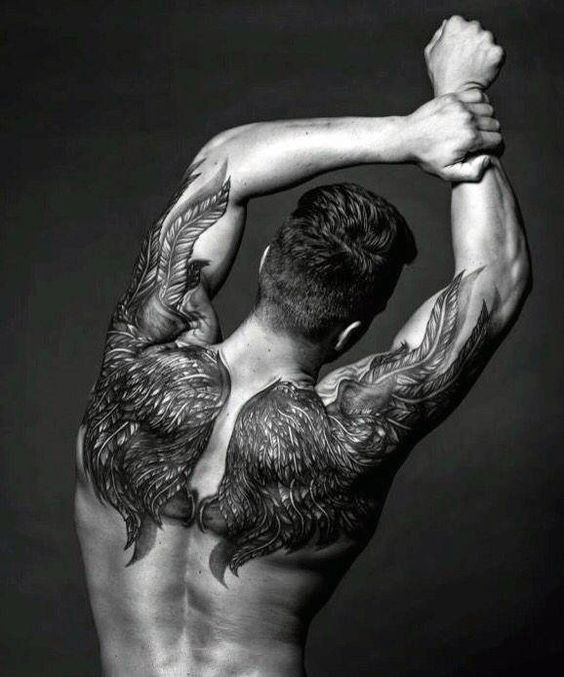 Close nas costas de um homem com tatuagem de asas que vão desde as costas até o braço