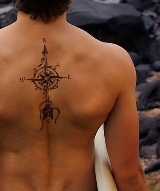 Um close de uma rosa dos ventos tatuada nas costas de um surfista.