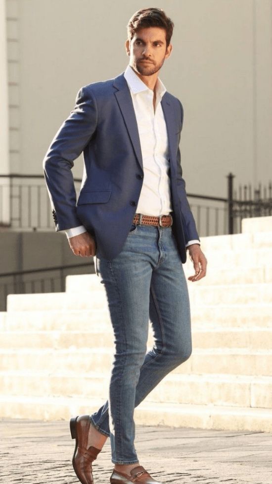 Homem branco com com look formal com camisa social branca, blazer azul, calça masculina jeans e sapato