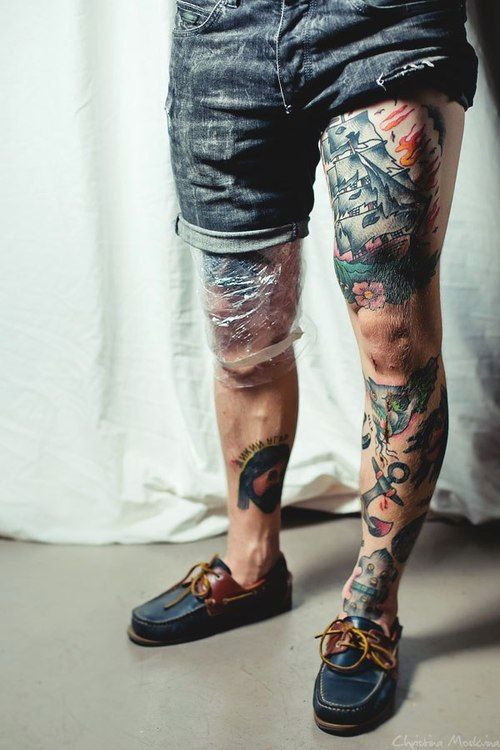 Close em pernas masculinas tatuadas com diversas estilos.